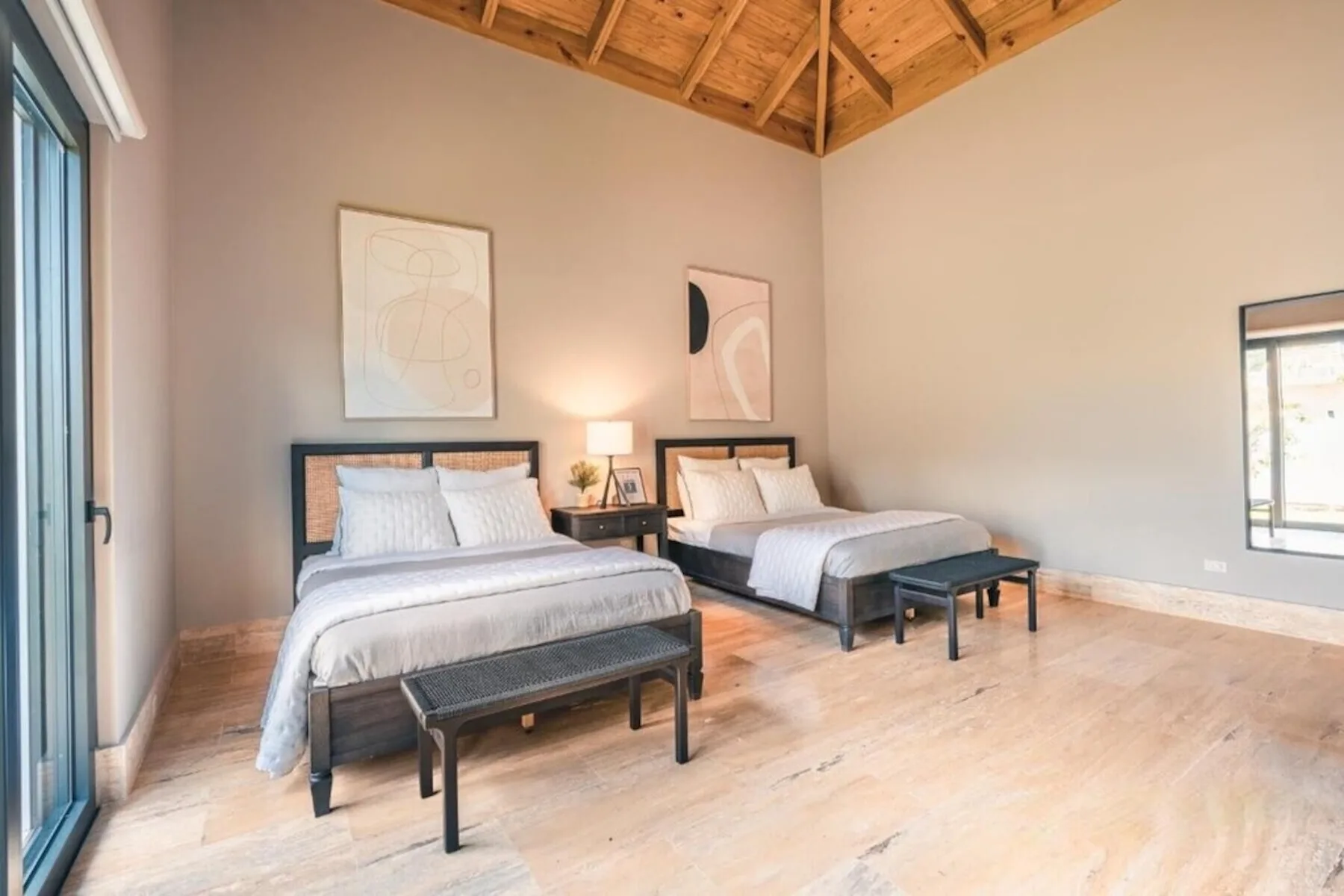 Un dormitorio luminoso con dos camas y un techo abovedado de madera.