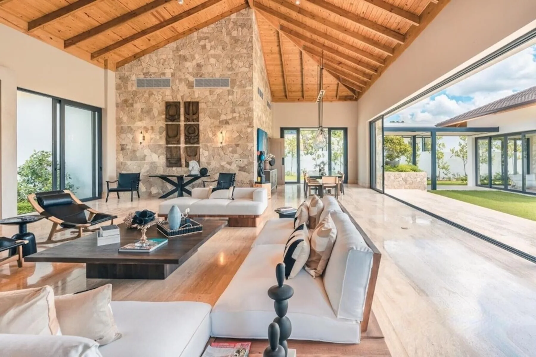 Una amplia sala de estar con asientos, una chimenea de piedra y grandes ventanales.