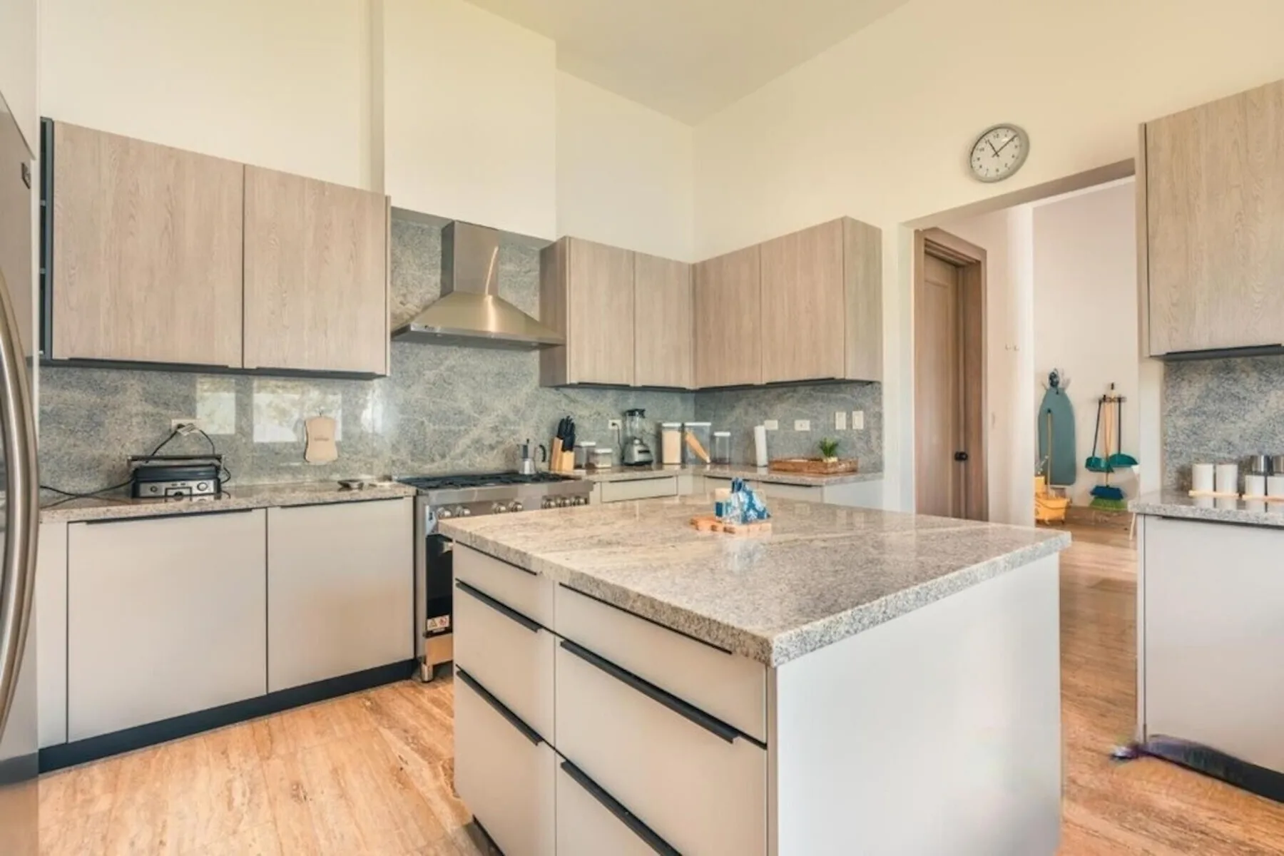 Una cocina luminosa con una isla central y gabinetes de madera clara.