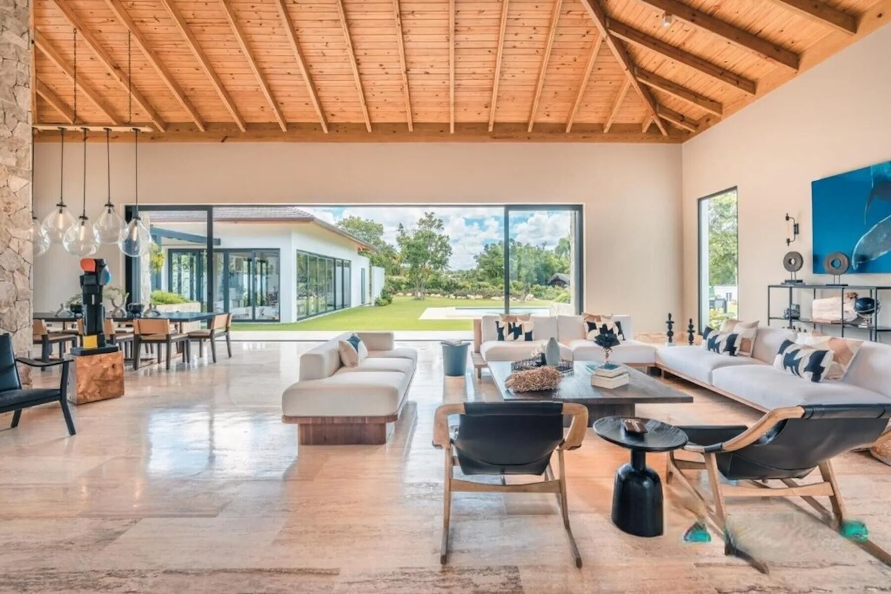 Una amplia sala de estar y comedor de concepto abierto, con grandes ventanales hacia un jardín.