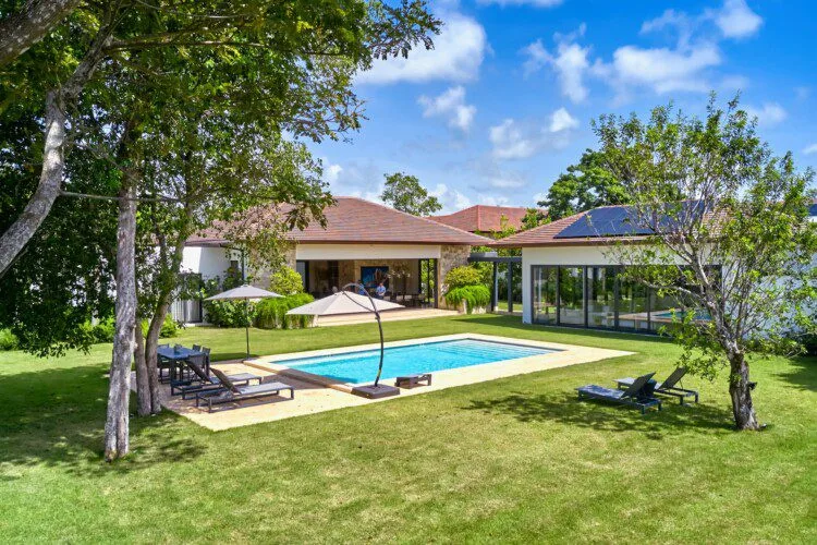 Un jardín ajardinado con piscina junto a una casa moderna de una planta.