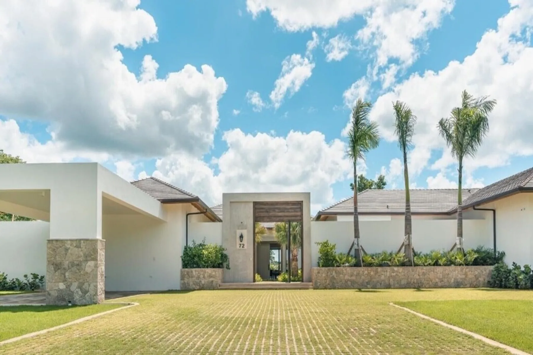 La entrada de un edificio blanco moderno da a un camino pavimentado y un jardín.