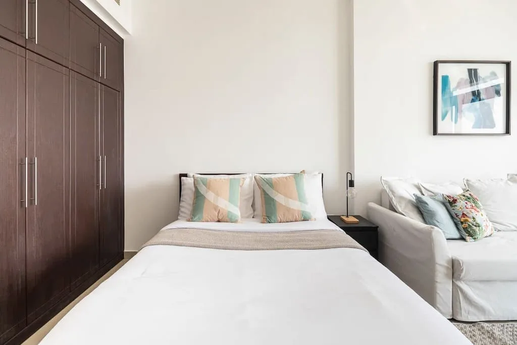 Un dormitorio con una cama bien arreglada junto a una zona de estar.