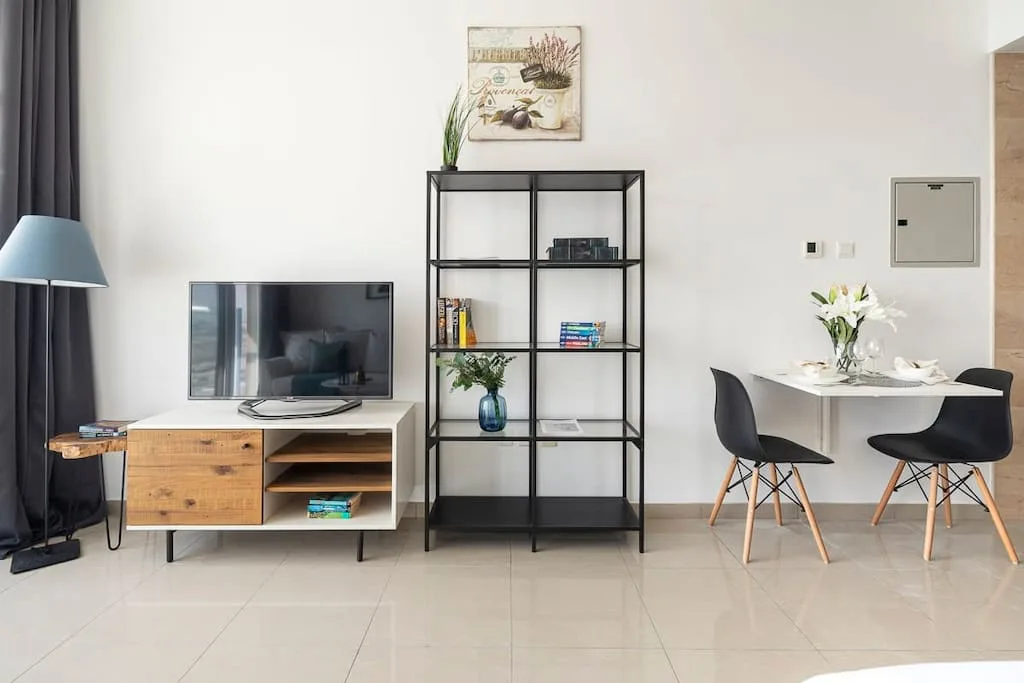 Sala de estar y comedor con televisor, estantería y una mesa con sillas.