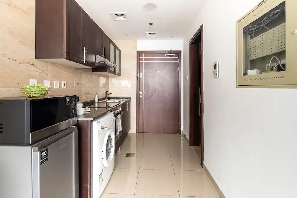 Una cocina compacta con zona de lavandería, armarios oscuros y una lavadora.