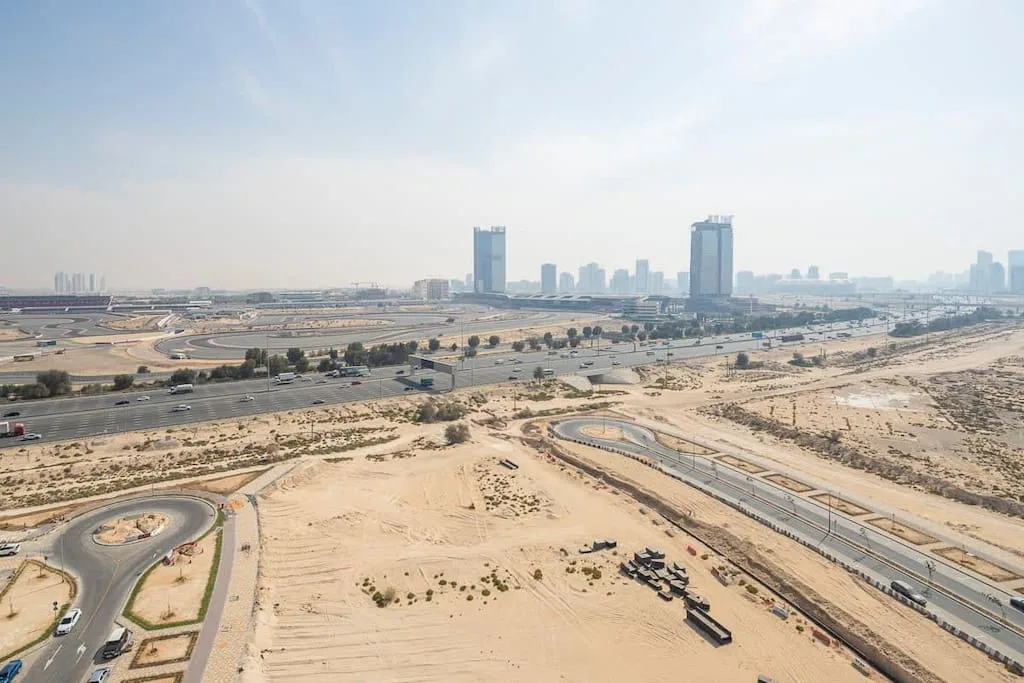 Una amplia zona arenosa en construcción ocupa el primer plano, con carreteras y una ciudad al fondo.