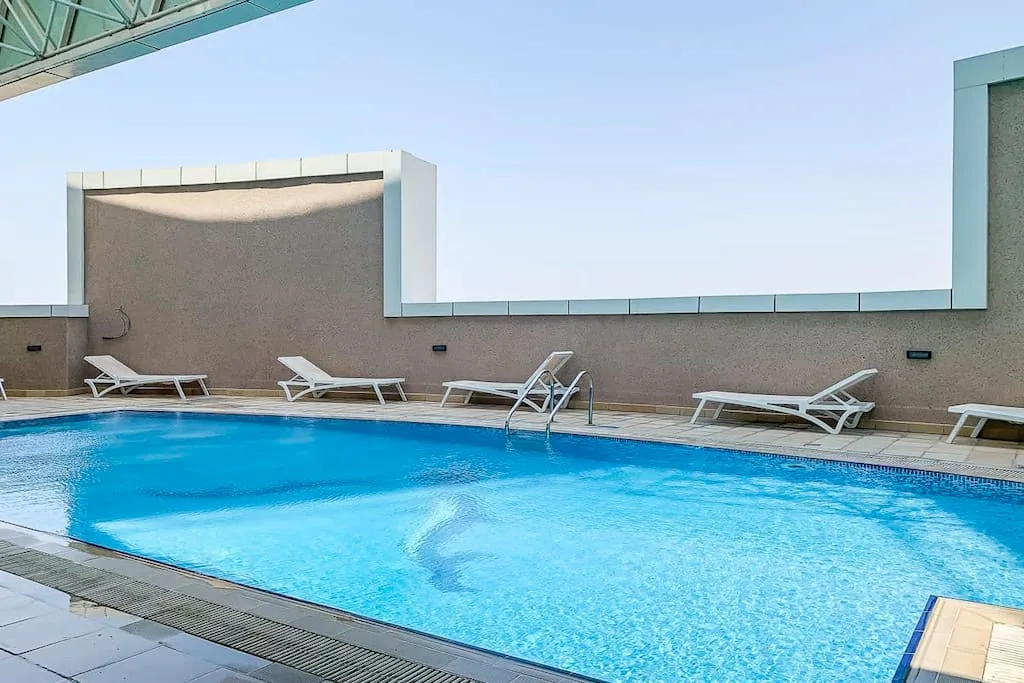Una piscina en la azotea con tumbonas está bajo un cielo despejado.