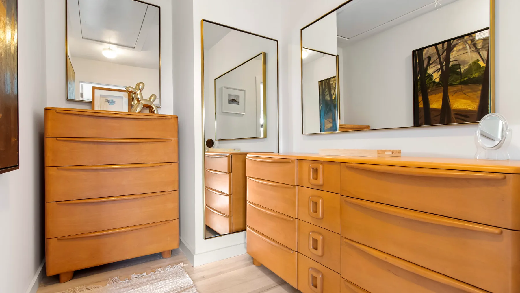 Un área de vestidor con cómodas de madera y grandes espejos de pared.