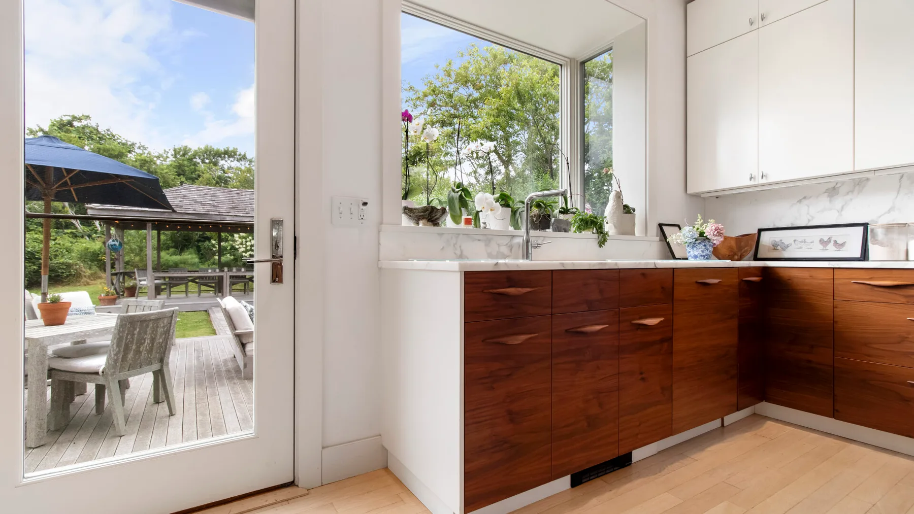 Una cocina luminosa con gabinetes de madera oscura y una gran ventana con vista a la vegetación.