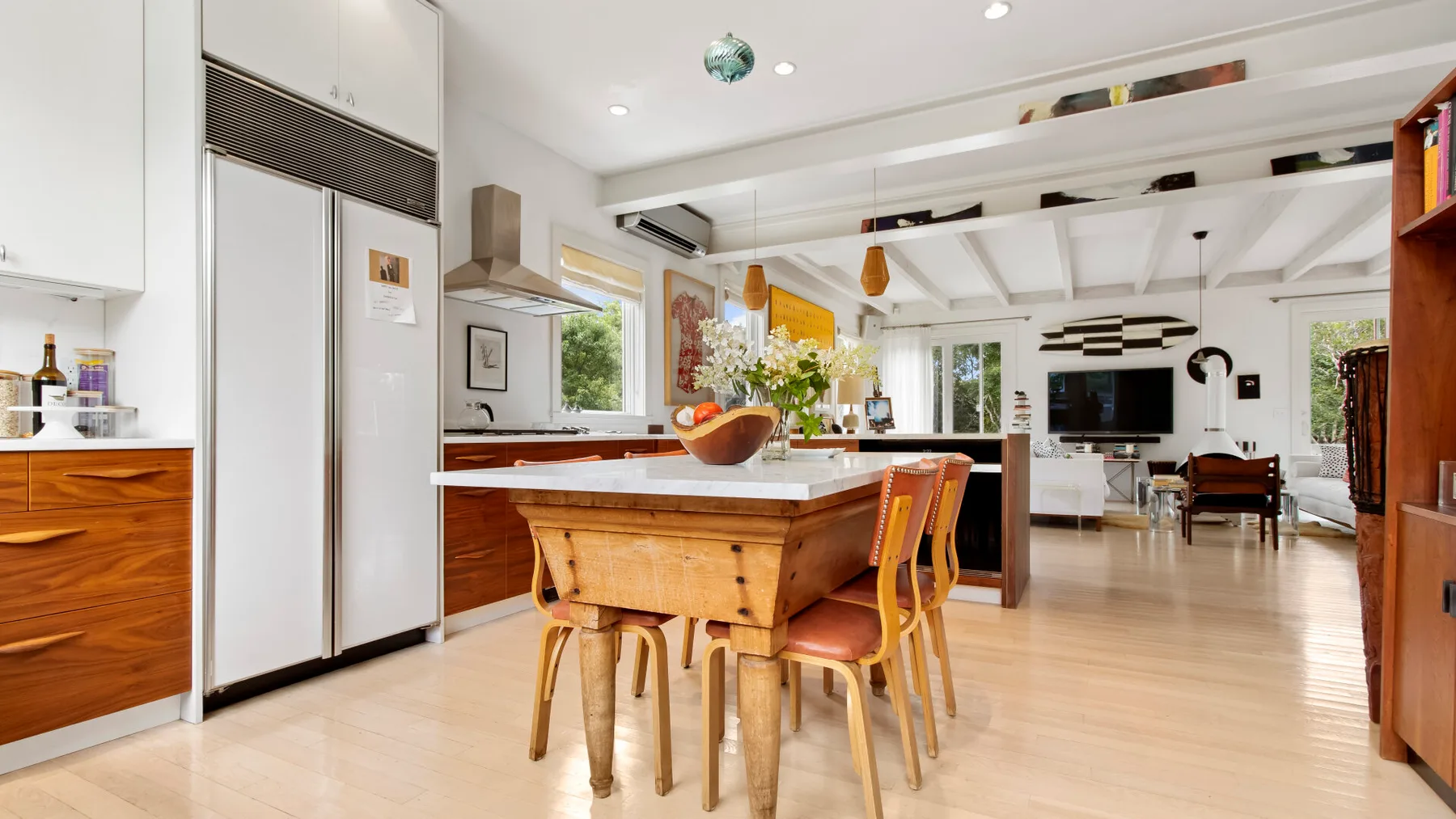 Una luminosa cocina-comedor de planta abierta con una mesa de madera e isla.