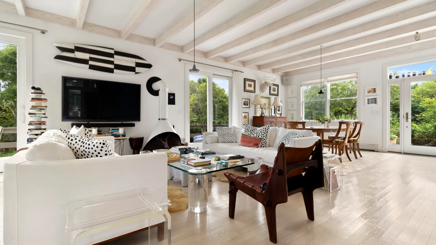 Una sala luminosa con asientos, un televisor y grandes ventanas.