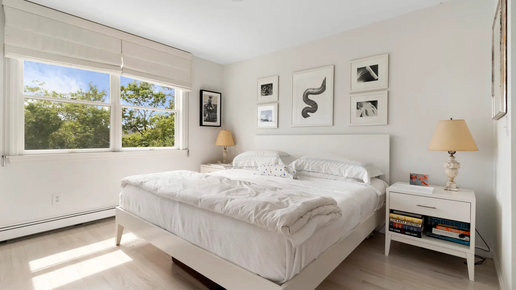 Un dormitorio luminoso con una cama bien hecha y ventanas amplias.