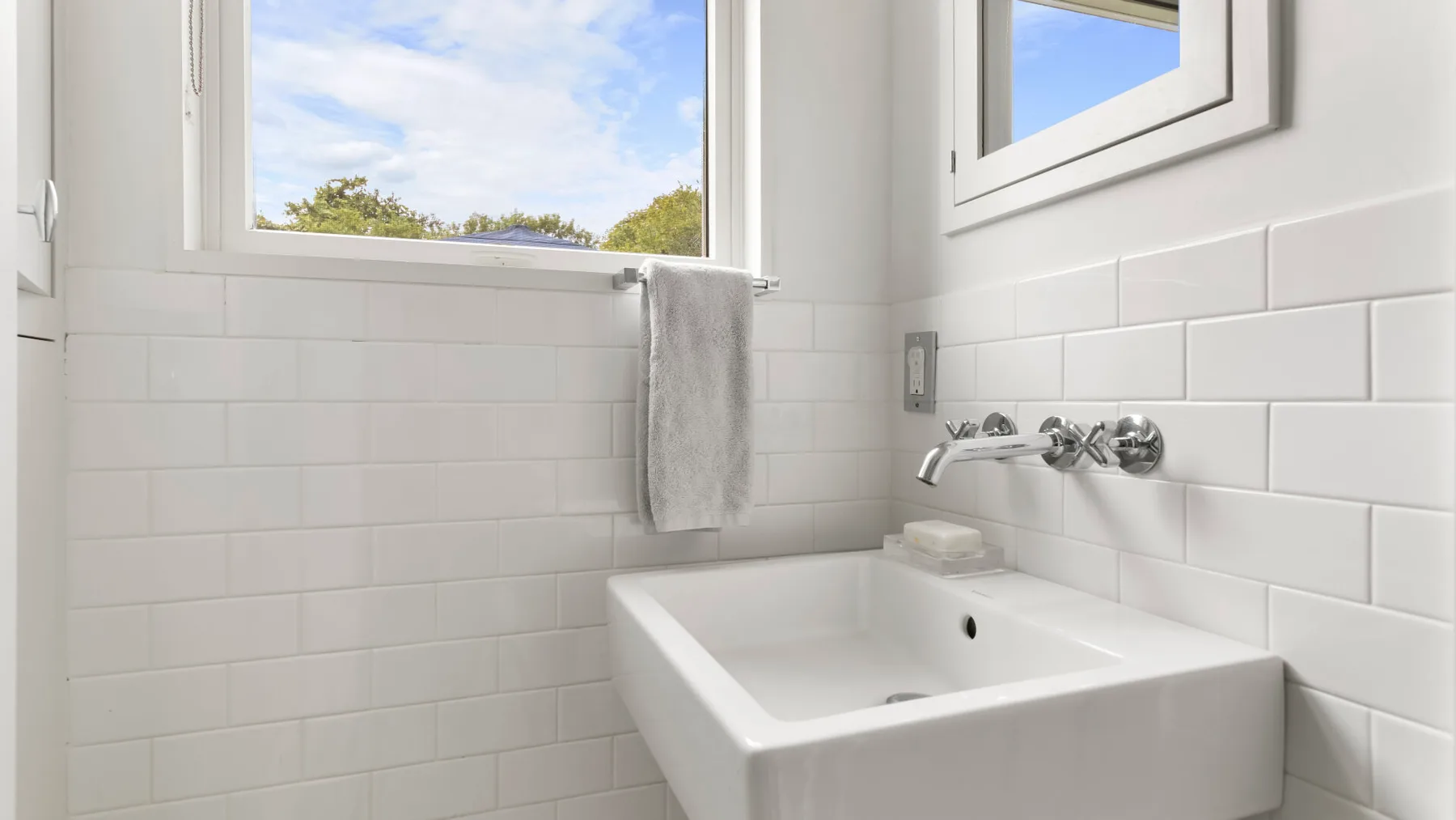 Un baño luminoso con un lavabo blanco bajo una ventana.