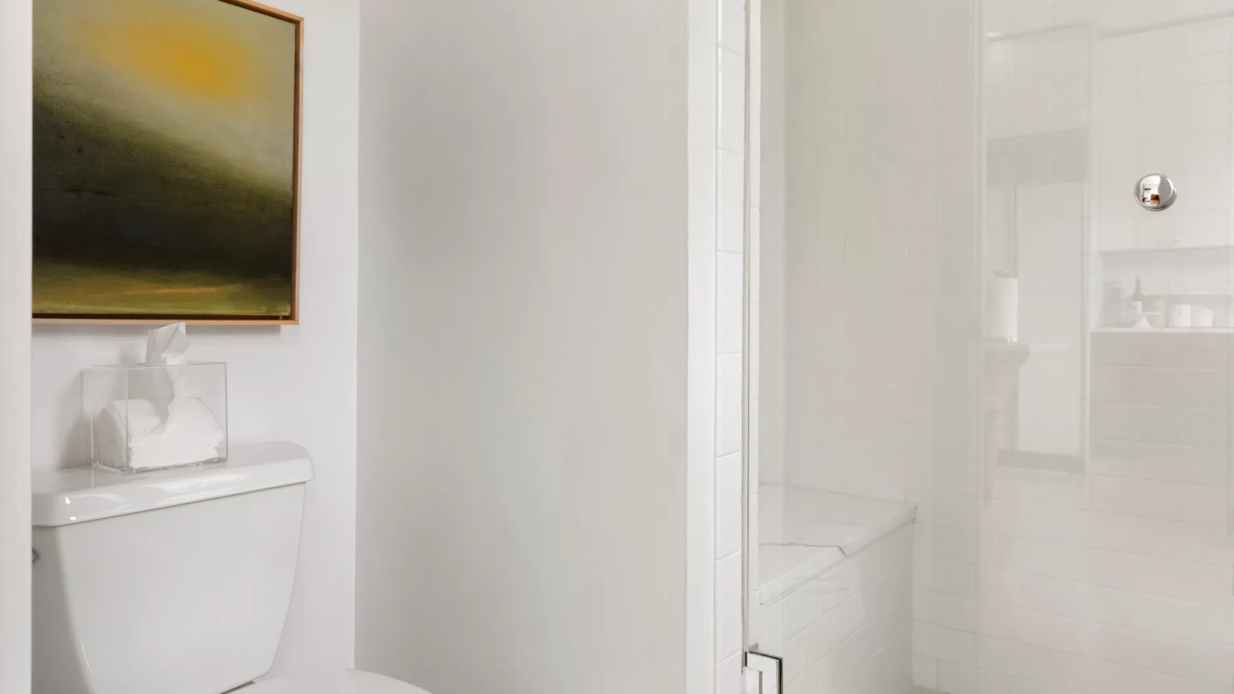 Un baño luminoso con inodoro, lavabo y ducha de vidrio.