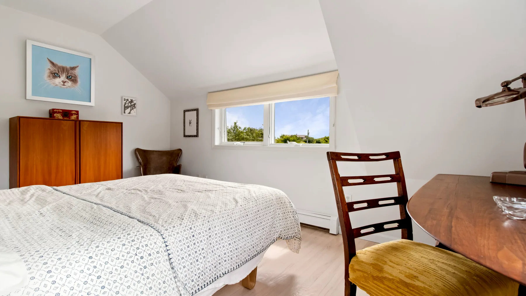 Un dormitorio con una cama, una ventana y un escritorio de madera.