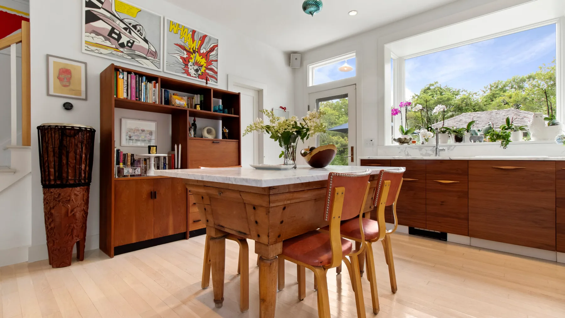 Una cocina luminosa con una isla de madera, asientos y grandes ventanas.