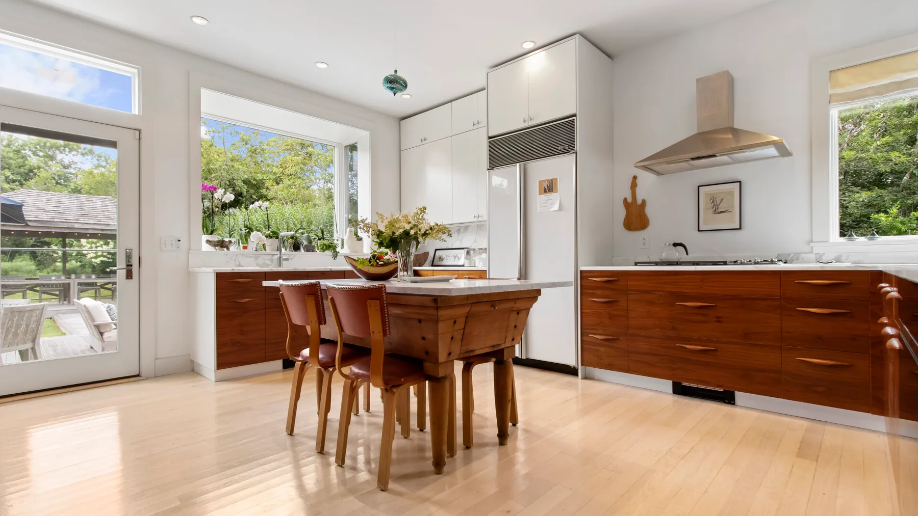 Una cocina luminosa con una mesa de comedor de madera y ventanas grandes.