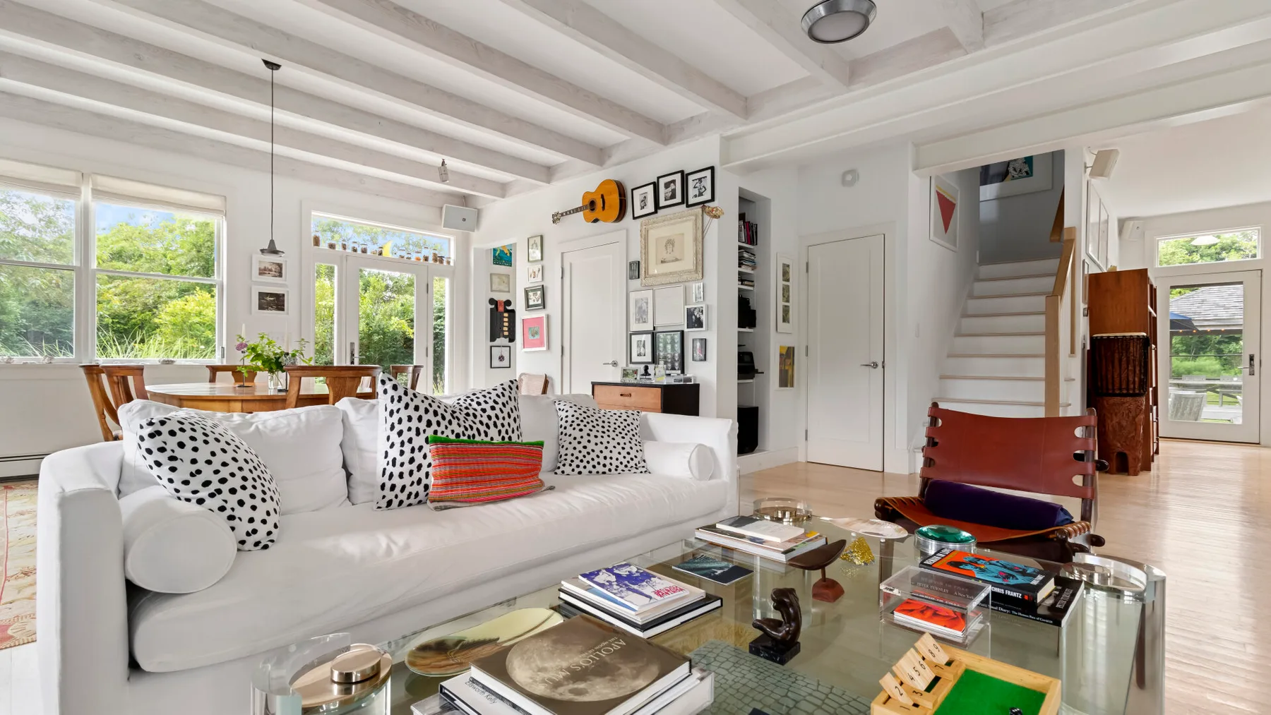 Una sala luminosa con asientos blancos, una mesa de centro de vidrio y grandes ventanas.