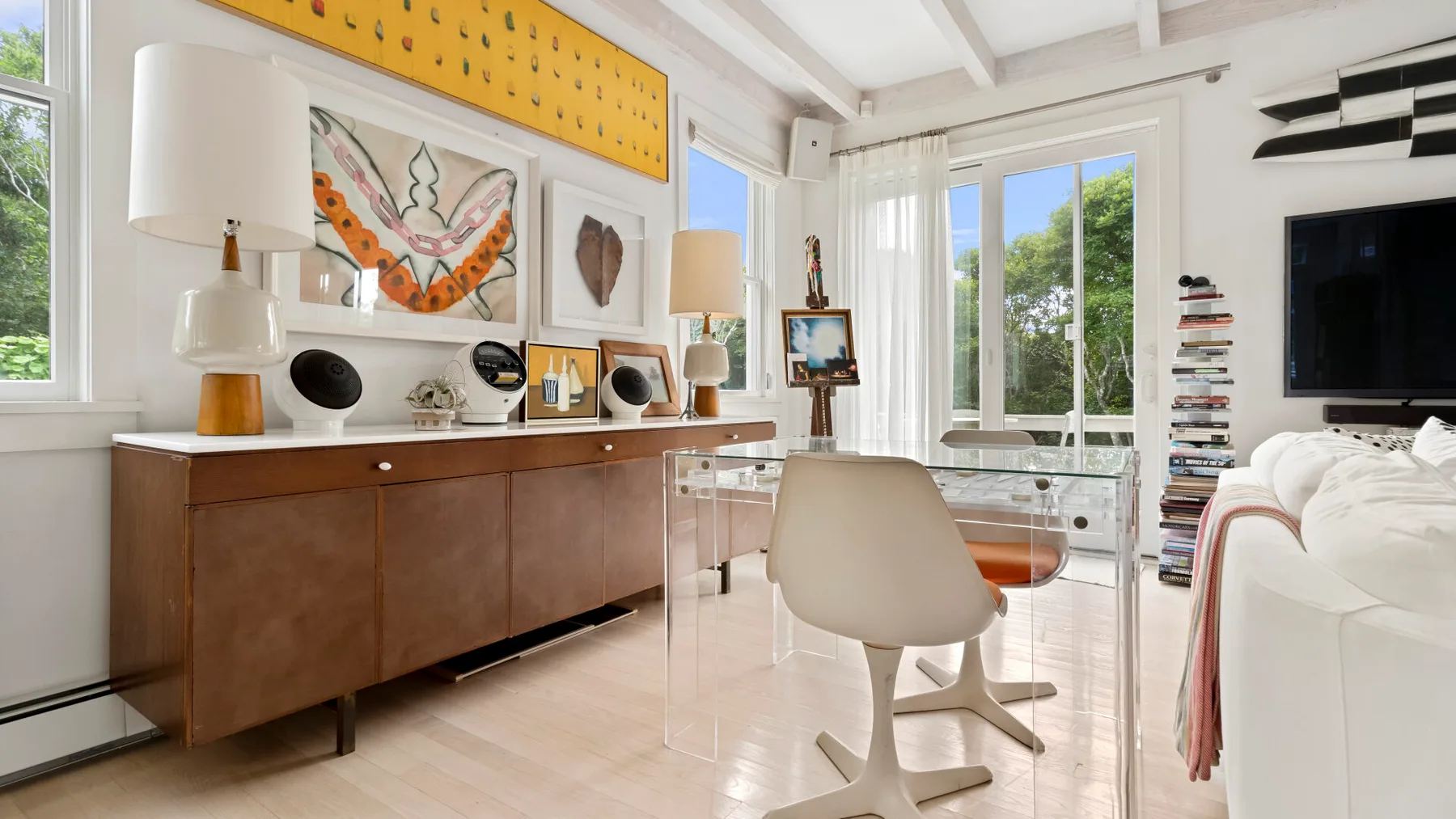 Una sala luminosa con mesa, asientos y ventanas grandes.