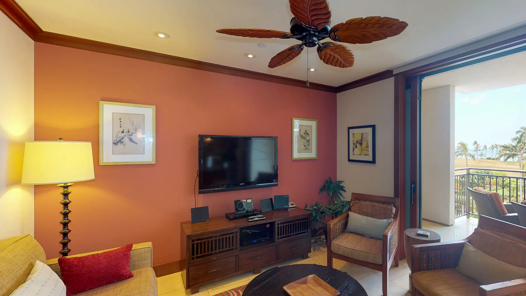 A living room with seating, a television, and a sliding glass door opening to a balcony.