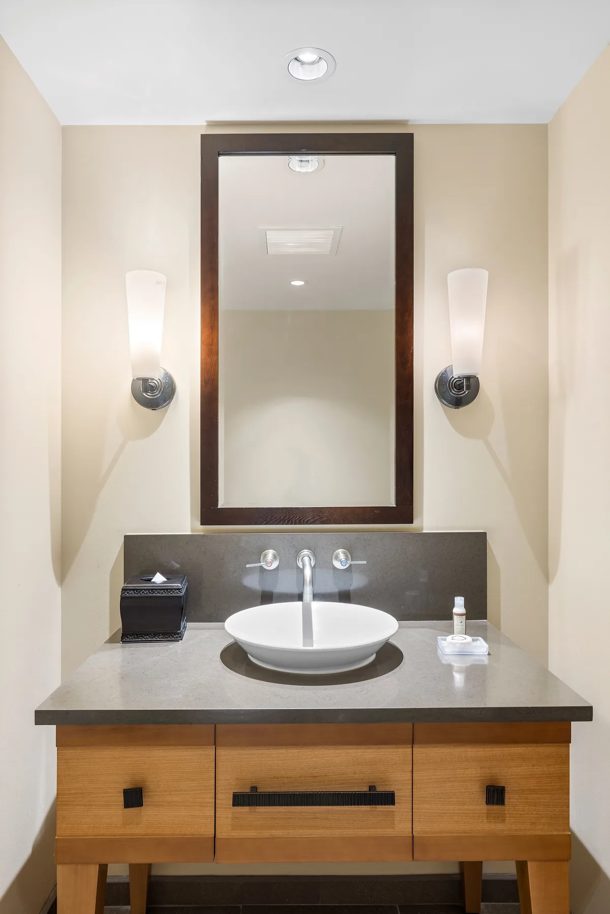 A bathroom vanity with a sink, mirror, and wall lights.