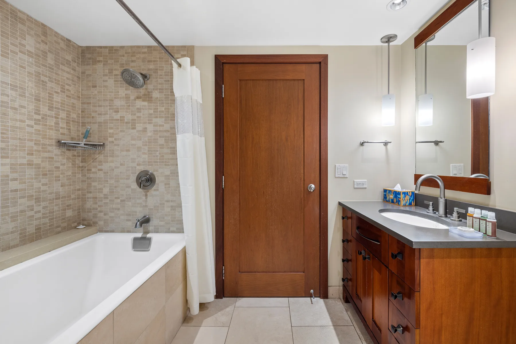 A bathroom with a bathtub, tiled shower wall, and wooden vanity.