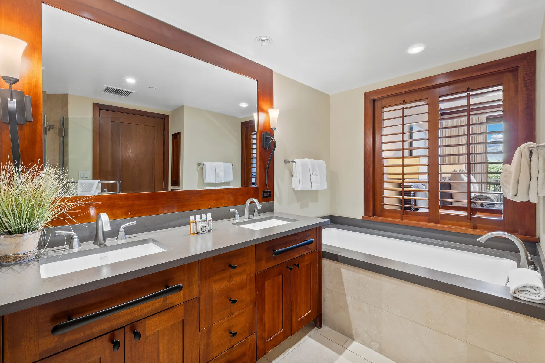 A bathroom with a double vanity and a bathtub beside a window.