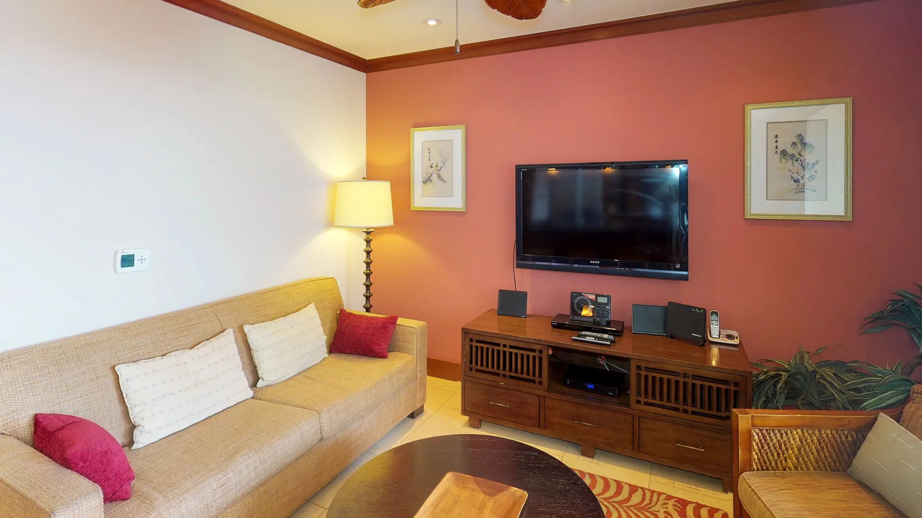 A living room with a television above a wooden entertainment console and seating.