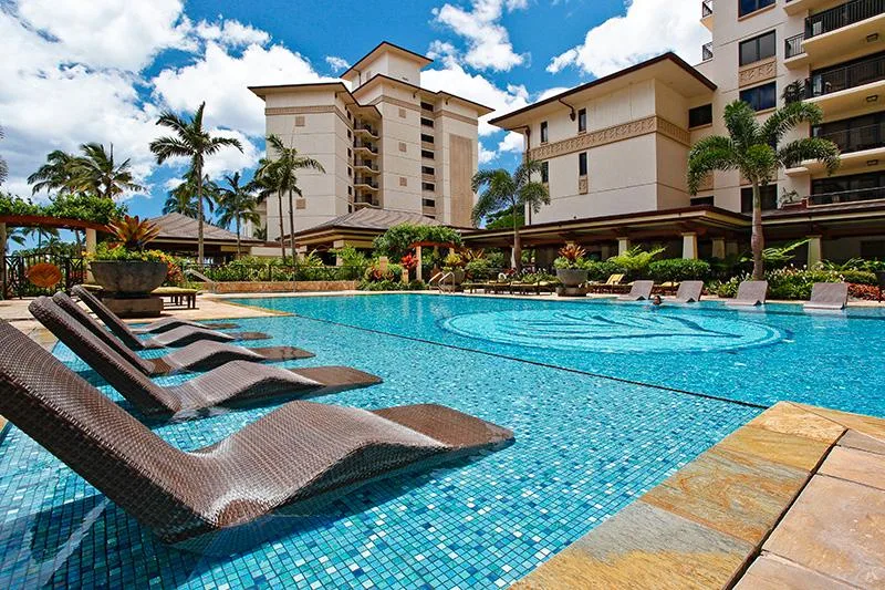 A swimming pool is surrounded by lounge seating and multi-story buildings.