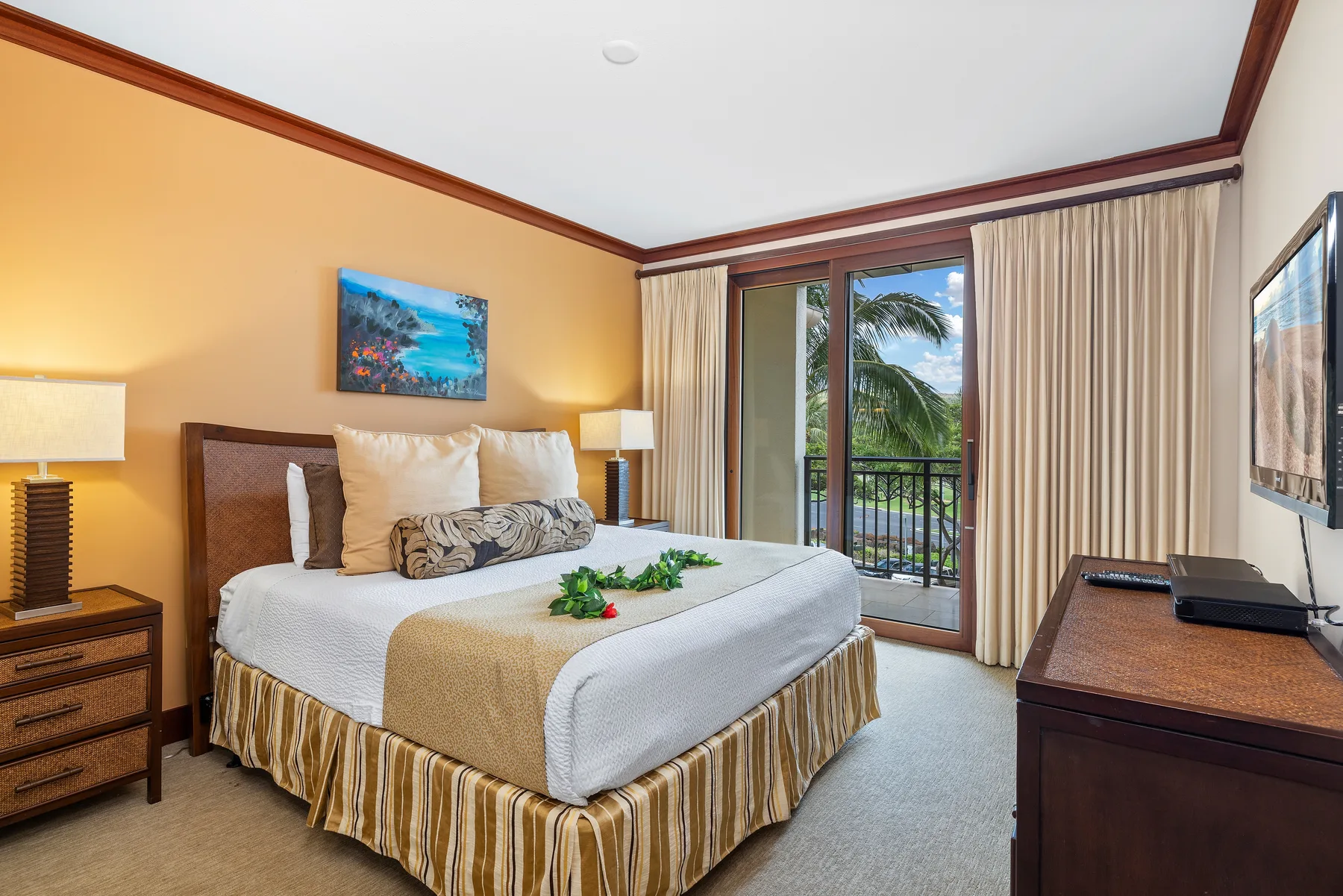 A bedroom with a made bed, bedside lamps, and glass doors opening onto a balcony.