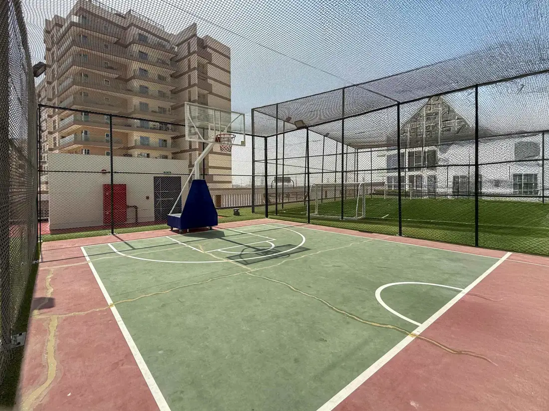 Una cancha deportiva al aire libre con líneas pintadas y una canasta de baloncesto.