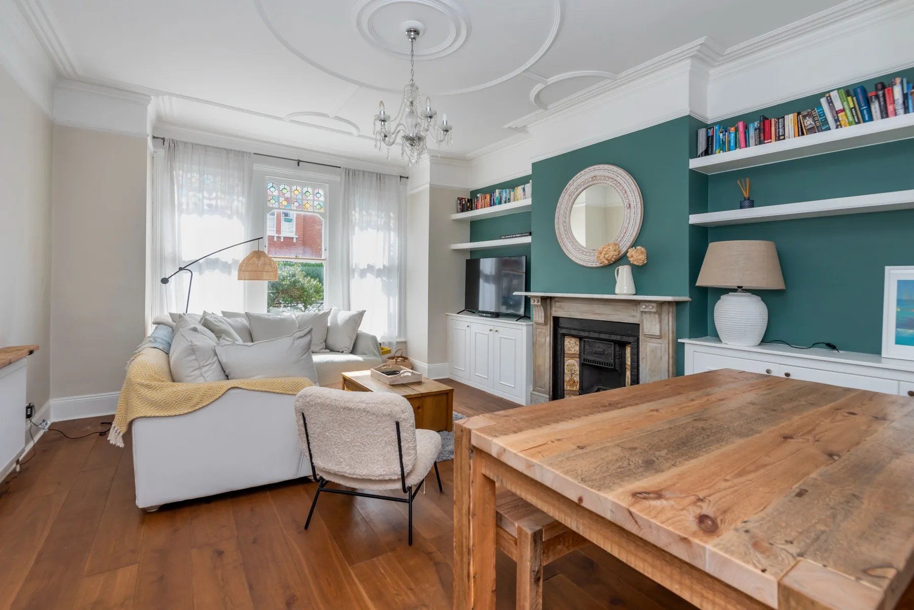 A bright living room with seating, a fireplace, and a wooden dining table.