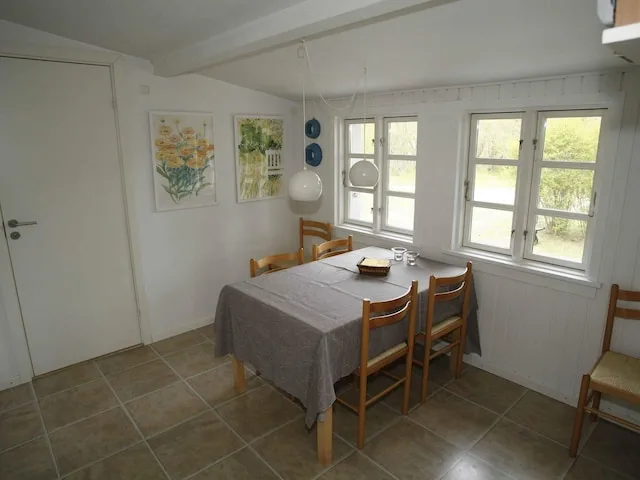 A dining area with a table and chairs beside several windows.