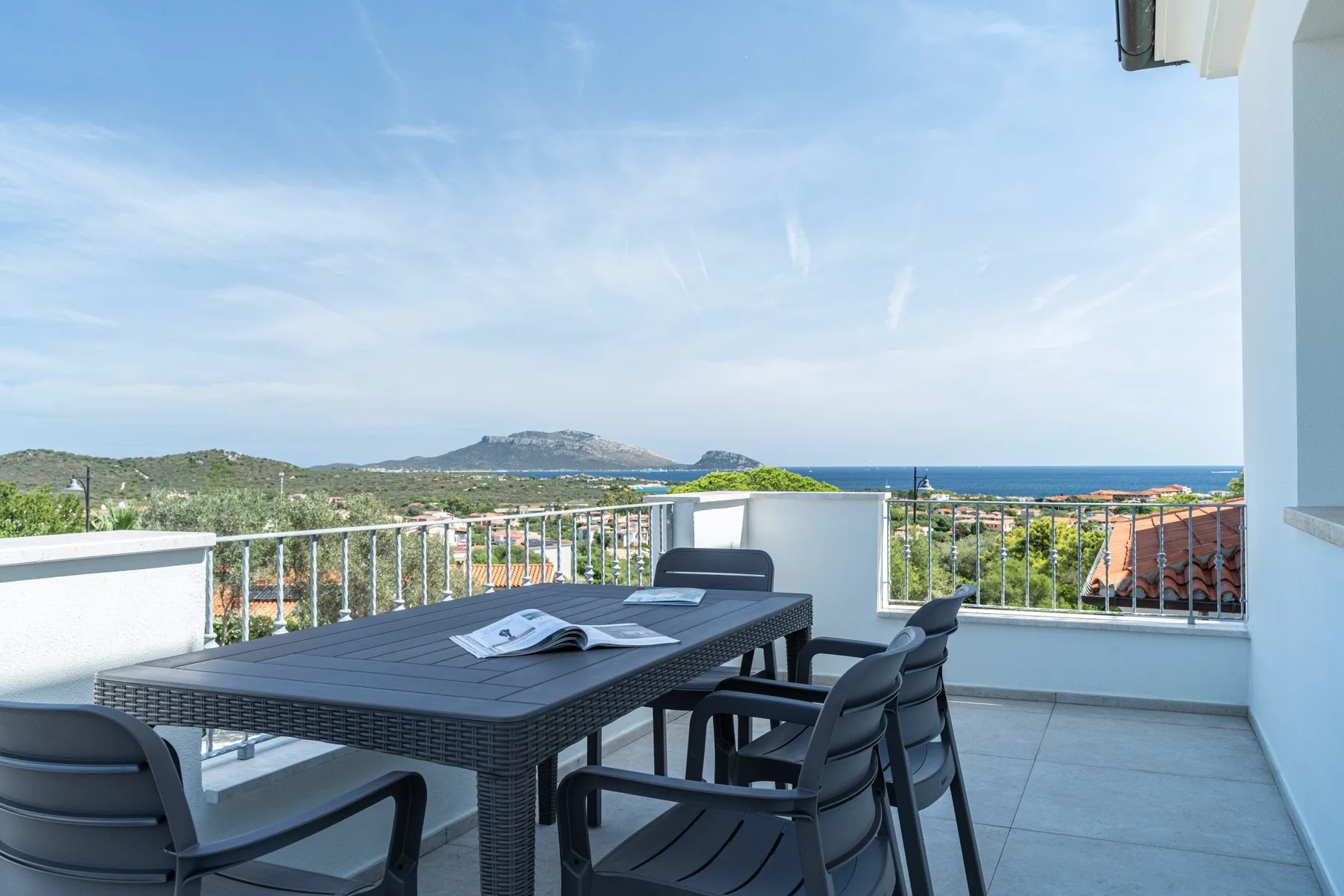 Una terraza en la azotea tiene una mesa y sillas al aire libre con vistas al mar.
