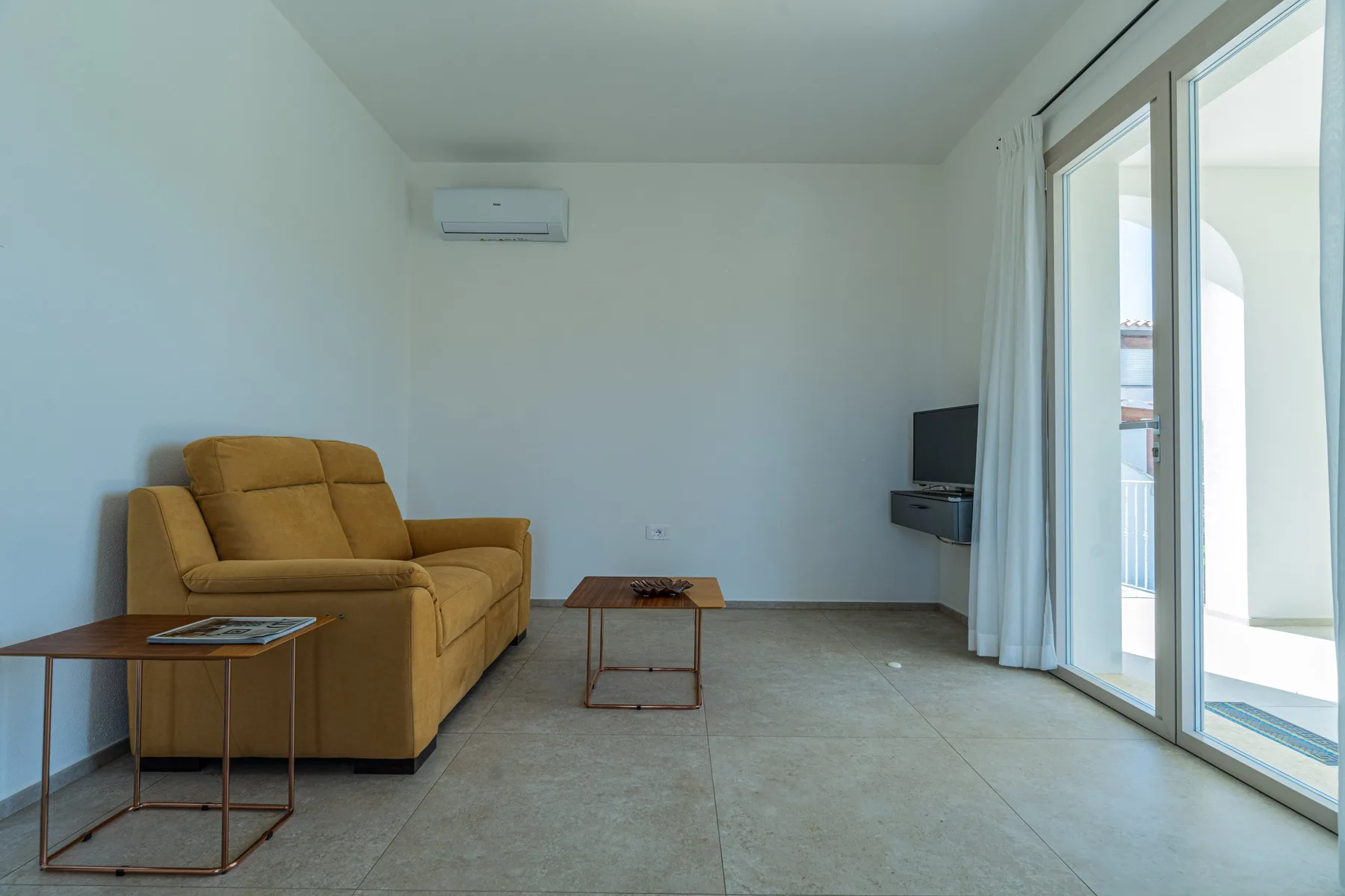 Una sala de estar con asientos, una mesa pequeña y puertas corredizas de vidrio.