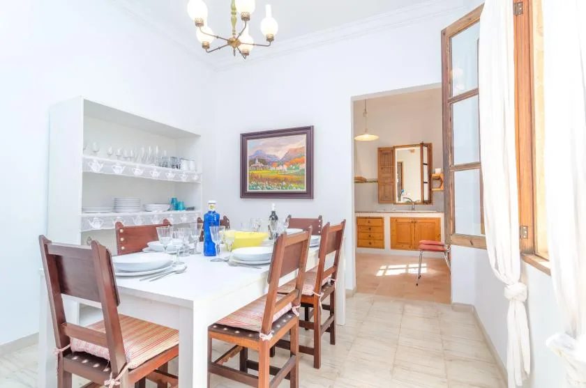 A bright dining area with a set table and an open view into the kitchen.
