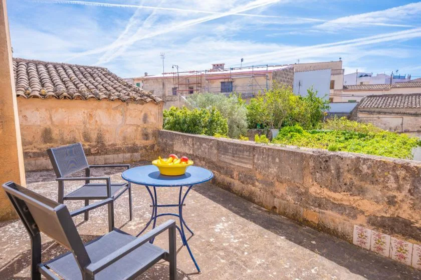 A sunlit rooftop terrace with seating and a small table topped with fruit.
