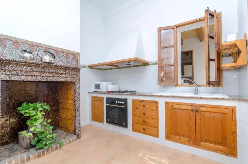 A kitchen with wooden cabinets, a countertop, and a tiled fireplace.