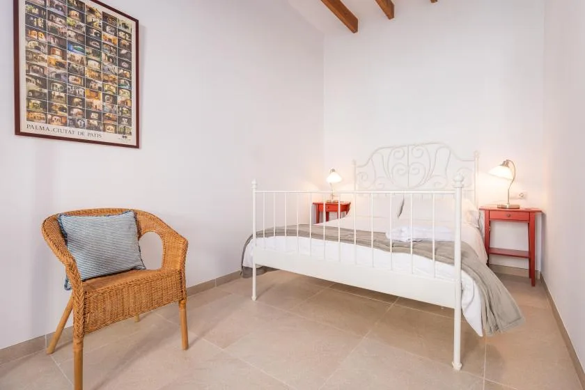 A bedroom with a white bed, wicker seating, and matching bedside tables.