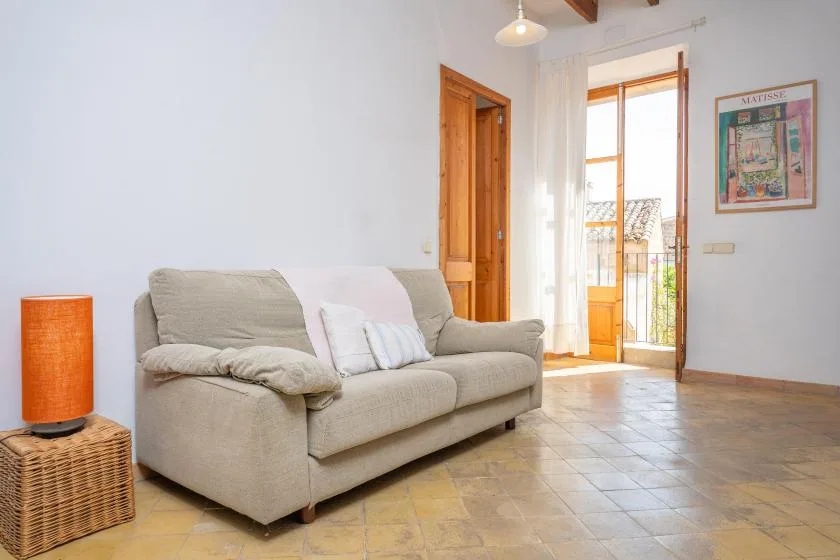 A living room with a sofa and a glass door opening onto a balcony.