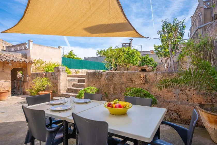 An outdoor dining area with a table and seating beneath a shade canopy.