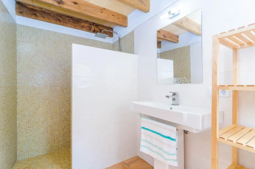 A bathroom with a tiled shower area, sink, and mirror.
