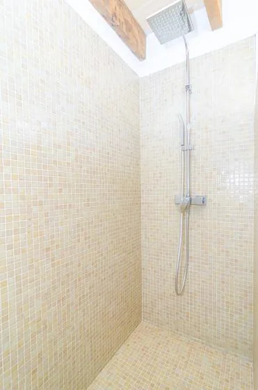 A tiled shower area with a rainfall showerhead and handheld shower.