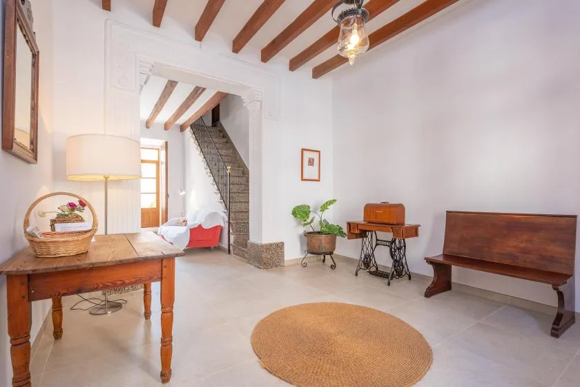 A bright living room features exposed ceiling beams and a wooden bench.