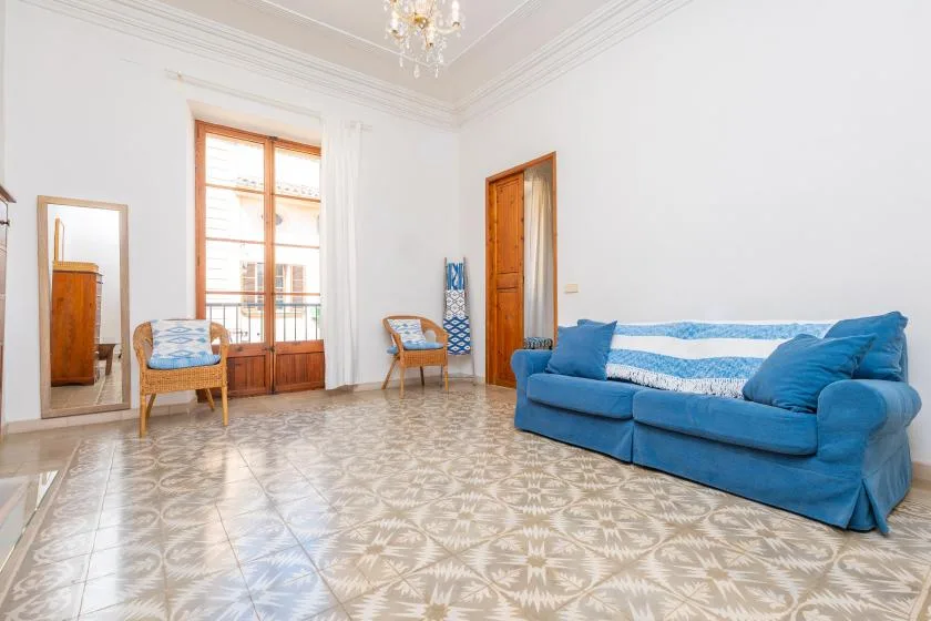 A bright living room with blue seating and patterned tile flooring.