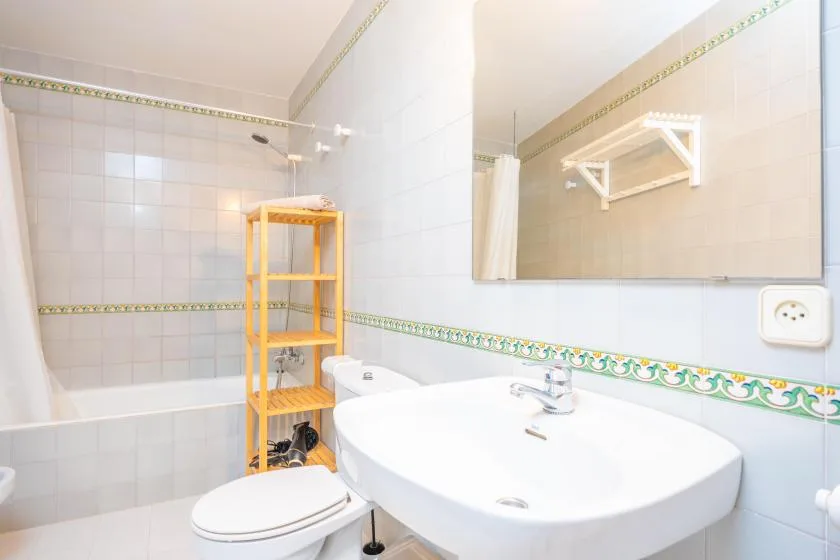 A tiled bathroom with a bathtub, toilet, and large sink.