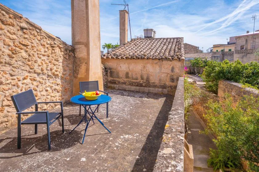 A rooftop terrace with outdoor seating and a small blue table overlooks neighboring buildings.