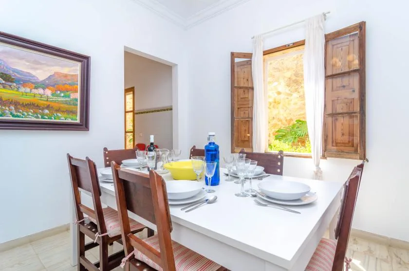 A dining room with a table set with dishes beside a window.