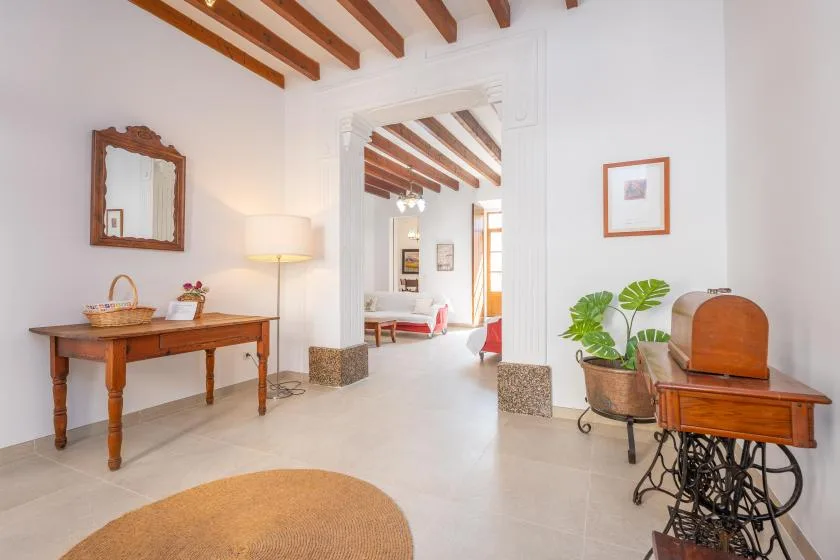 A bright interior hallway connects two rooms, with wooden furniture and ceiling beams.