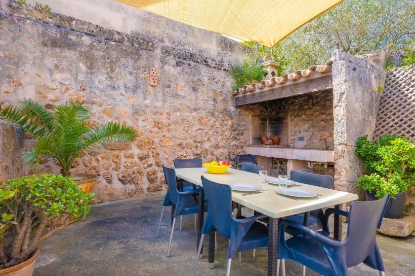 An outdoor dining area with a table and chairs beside a stone barbecue.